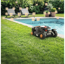 Scéna s robotickou kosačkou na trávniku vedľa bazéna, ležadlami a rastlinami