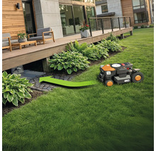 Robotická kosačka na trávu ide po trávniku smerom k nabíjacej stanici.