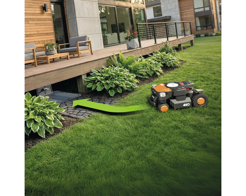 Robotická kosačka na trávu ide po trávniku smerom k nabíjacej stanici.