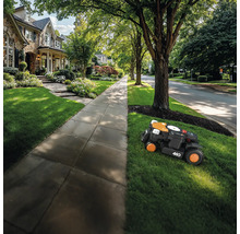 Robotická kosačka kosí trávnik pred domom.