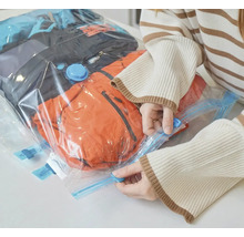 Žena uzatvára vákuový sáčok s oblečením na uskladnenie.