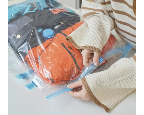 Žena uzatvára vákuový sáčok s oblečením na uskladnenie.