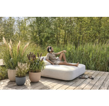 Scéna s mužom oddychujúcim na vonkajšej pohovke, obklopeným črepníkovými rastlinami