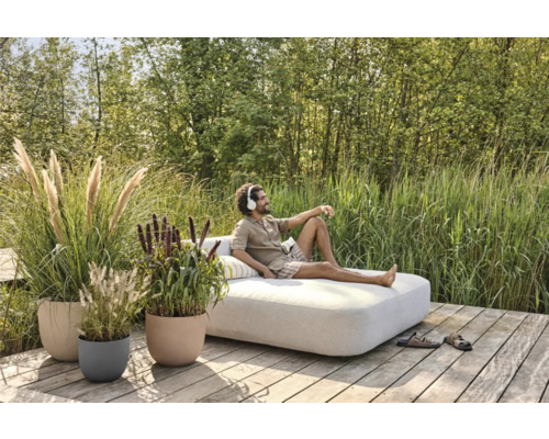 Scéna s mužom oddychujúcim na vonkajšej pohovke, obklopeným črepníkovými rastlinami