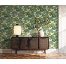 Obývacia izba s tapetou so vzorom stromov, drevenou komodou, stolnou lampou a vázou