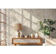 Obývacia izba s botanickou tapetou, lampou, dekoráciou a rastlinou na drevenej skrinke.