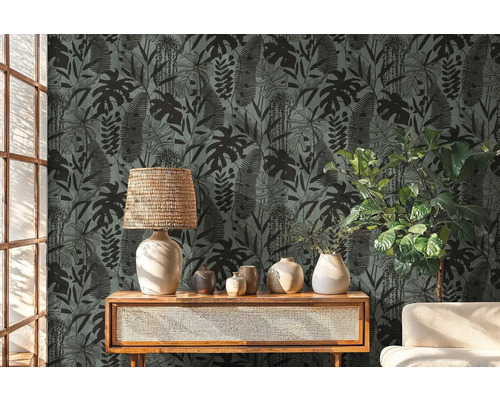 Dekoratívna izba s tapetou s motívom tropických rastlín, lampou a rastlinami na drevenom nábytku.