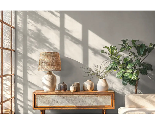 Svetlá obývacia izba s konzolovým stolíkom, lampou, vázami a izbovou rastlinou