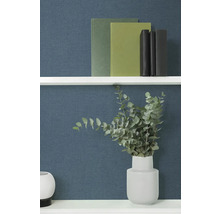 Dekoratívne knihy a eukalyptus vo váze na polici.