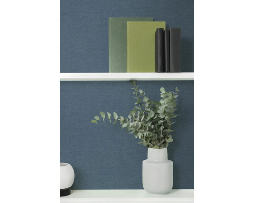 Dekoratívne knihy a eukalyptus vo váze na polici.
