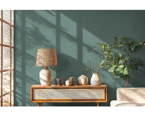 Obývacia izba s komodou, lampou, vázami a izbovou rastlinou pred stenou