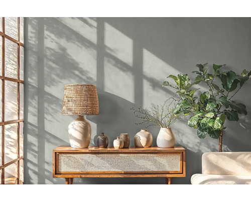 Obývacia izba so stolnou lampou, dekoráciou a rastlinou na drevenej skrini.