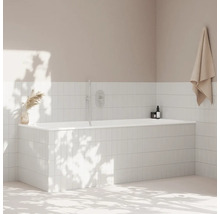 Kúpeľňa s bielou obloženou vaňou, uterákom a dekoráciou