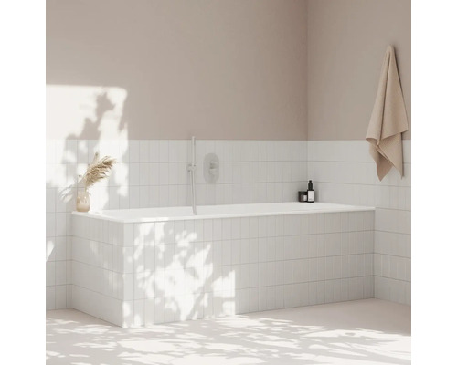 Kúpeľňa s bielou obloženou vaňou, uterákom a dekoráciou