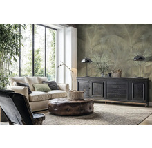 Moderná obývacia izba so svetlou pohovkou, koženým taburetom a vliesovou fototapetou s motívom paliem na stene za komodou.