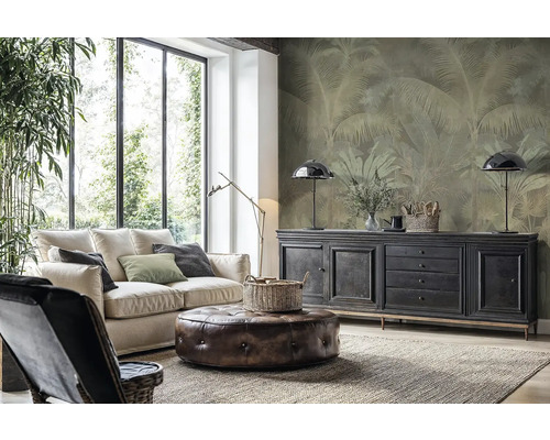 Moderná obývacia izba so svetlou pohovkou, koženým taburetom a vliesovou fototapetou s motívom paliem na stene za komodou.