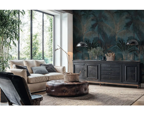 Obývacia izba s fototapetou s motívom paliem v tmavomodrej a zlatej farbe, svetlou pohovkou, koženým taburetom a čiernou komodou pri veľkých oknách.