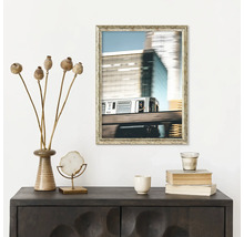 Dekoratívne usporiadanie s komodou, zarámovanou fotografiou a rôznymi dekoratívnymi predmetmi, ako je váza s makmi, stoh kníh a šálka