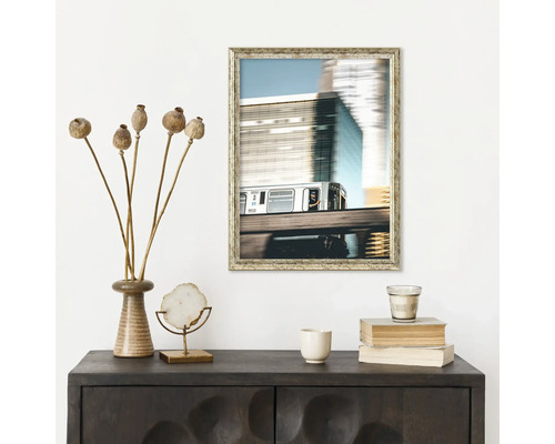 Dekoratívna scéna so skrinkou, zarámovaným obrázkom vlaku, maky, dekorom a knihami.