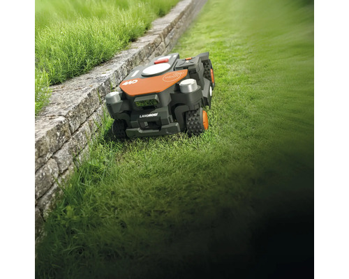 Robotická kosačka Landroid na trávniku vedľa steny