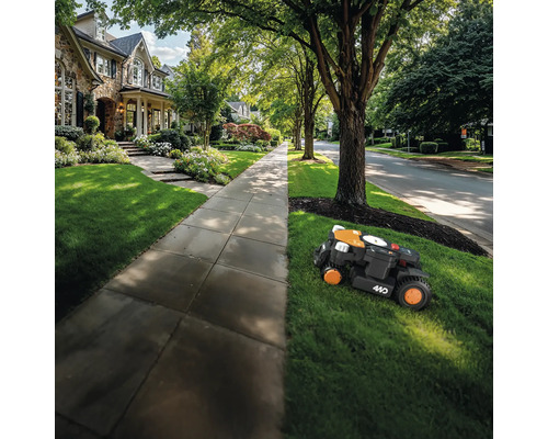 Robotická kosačka kosí trávnik pred obytným domom.