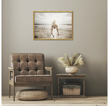 Dekoratívna obývacia izba s kreslom, stolom a zarámovaným plážovým obrázkom