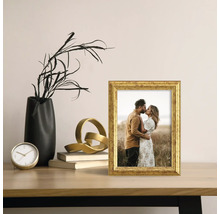 Dekoratívny zlatý fotorámik s fotografiou na stole