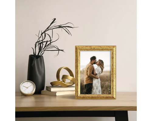 Dekoratívny zlatý fotorámik na stole s ďalšími dekoratívnymi predmetmi