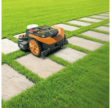 Robotická kosačka na trávniku s cestou z kamenných dosiek