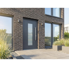 Moderný dom s vchodovými dverami so sklenenou vložkou, tehlovou fasádou a veľkými oknami