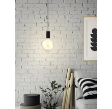 Závesná lampa s Edisonovou žiarovkou pred tehlovou stenou