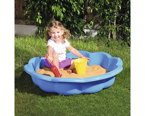 Dieťa sa hrá v modrom pieskovisku s hračkami do piesku v záhrade