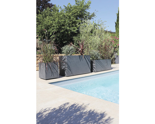 Tri sivé kvetináče rôznych veľkostí stoja na okraji bazéna a sú osadené rastlinami.