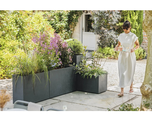 Pohľad do záhrady so sivými kvetináčmi a ženou nesúcou podnos