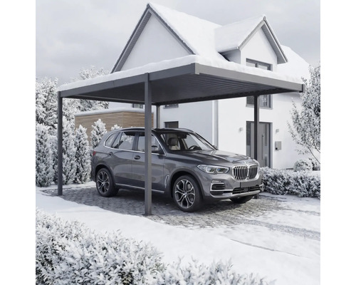 Auto stojí pod prístreškom pre auto pred domom v zime.