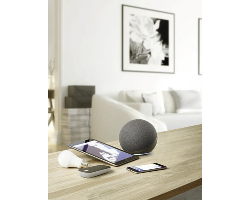 Snímka obývačky s inteligentnými domácimi zariadeniami, ako sú reproduktory, tablety, smartfóny a žiarovky na stole.