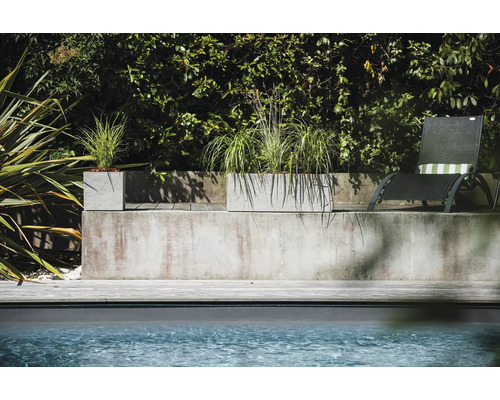 Betónové kvetináče s výsadbou vedľa bazéna a ležadla