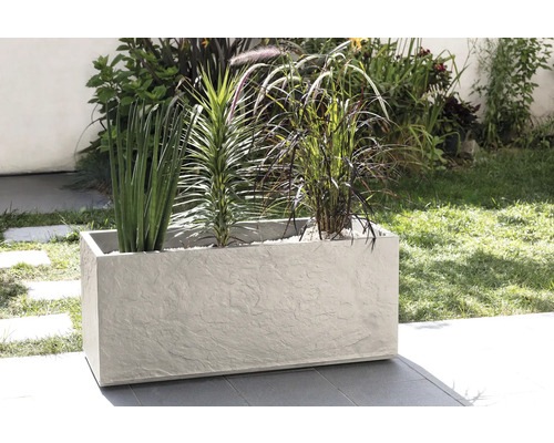 Obdĺžnikový kvetináč s rôznymi rastlinami vonku.