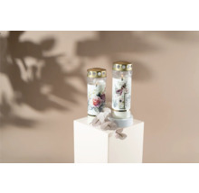 Dve cintorínske sviečky s kvetinovým vzorom na bielom podstavci