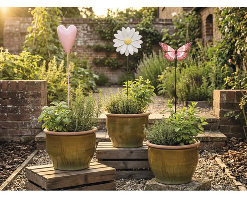 Tri kvetináče s bylinkami a ozdobné záhradné zápichy v tvare srdca, kvetiny a motýľa v záhrade.