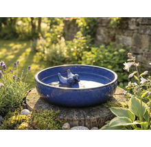 Modré pitítko pre vtáky s vtáčími figúrkami na pni v záhrade