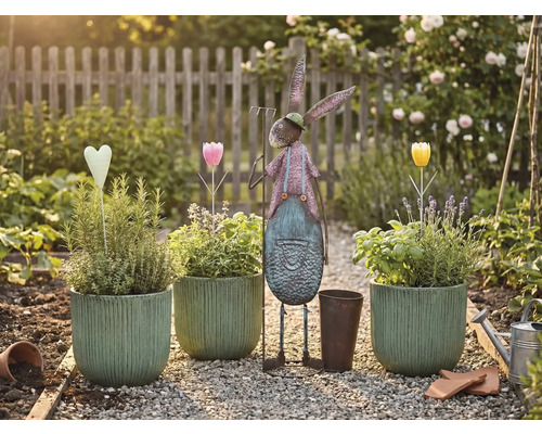 Záhradná scéna s osadenými kvetináčmi, kovovým zajacom a dekoráciami na štrkovej ceste