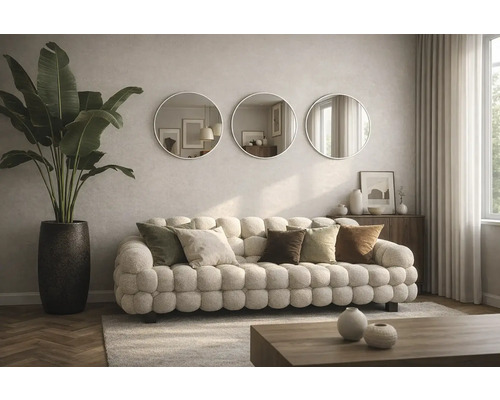 Obývacia izba s pohovkou, vankúšmi, okrúhlymi zrkadlami a izbovou rastlinou