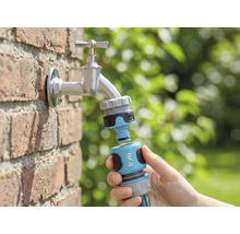 Záhradná scéna s vodovodným kohútikom, ku ktorému je v ruke pripojený konektor záhradnej hadice for_q