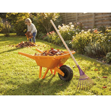 Záhradná scéna s fúrikom, hrabľami a dieťaťom zbierajúcim lístie