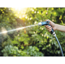 Ruka drží záhradnú striekaciu pištoľ for_q, z ktorej tryská prúd vody.