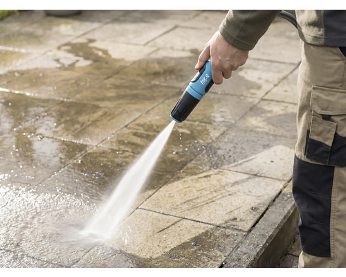 Osoba čistí kamennú terasu záhradnou hadicou for_q