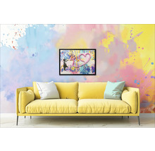 Žltá pohovka s vankúšmi pred stenou s orámovaným obrázkom dievčaťa a srdca