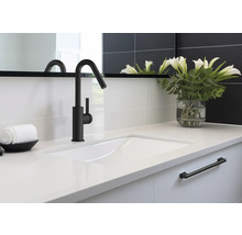 Umývadlo s čiernou batériou, uterákom a vázou s kvetinami v kúpeľni