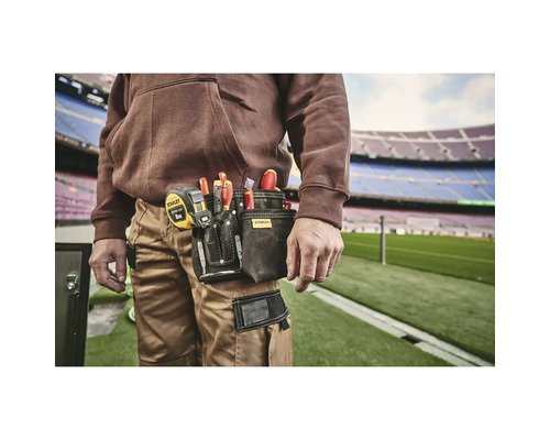 Remeselník s puzdrom na náradie na opasku, plným skrutkovačov a zvinovacieho metra od spoločnosti Stanley